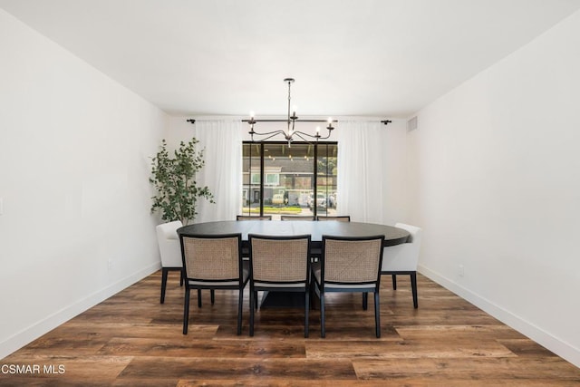 dining area with dark hardwood / wood-style flooring and a chandelier