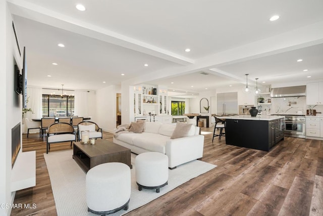 living room with beam ceiling, wood-type flooring, and an inviting chandelier