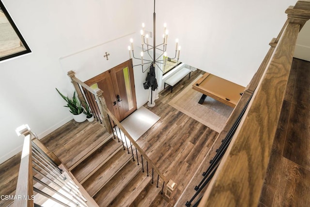 stairway with an inviting chandelier and hardwood / wood-style flooring