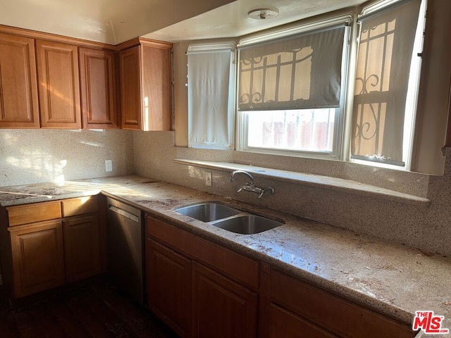 kitchen with light stone countertops, dishwasher, tasteful backsplash, and sink