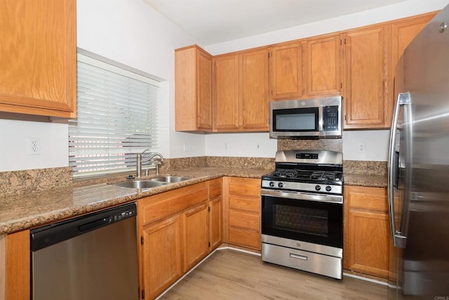 kitchen featuring stone counters, stainless steel appliances, light hardwood / wood-style flooring, and sink