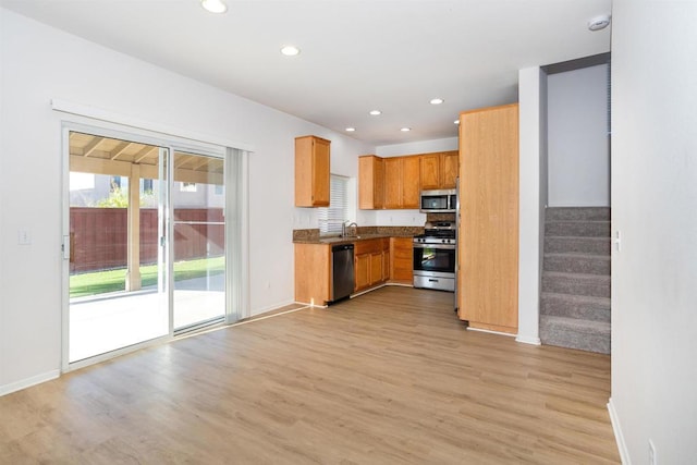 kitchen featuring light stone countertops, light wood-type flooring, appliances with stainless steel finishes, and sink