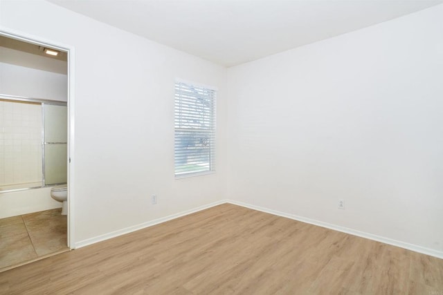 unfurnished bedroom featuring light wood-type flooring and ensuite bathroom