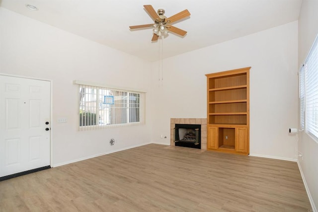 unfurnished living room with ceiling fan, a tile fireplace, and light hardwood / wood-style flooring