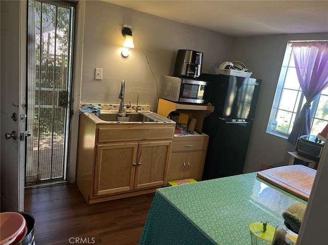 kitchen with black fridge, dark hardwood / wood-style flooring, and sink