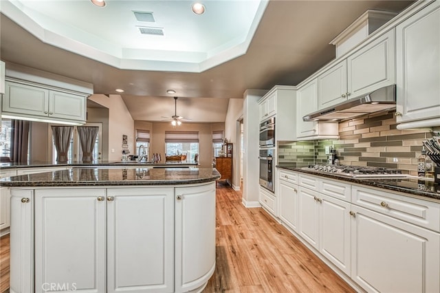 kitchen featuring white cabinets, kitchen peninsula, ceiling fan, and dark stone counters