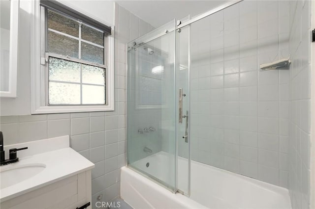 bathroom with tile walls, backsplash, shower / bath combination with glass door, and vanity