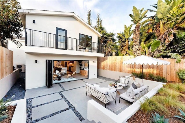 rear view of house with an outdoor living space, a patio area, and a balcony