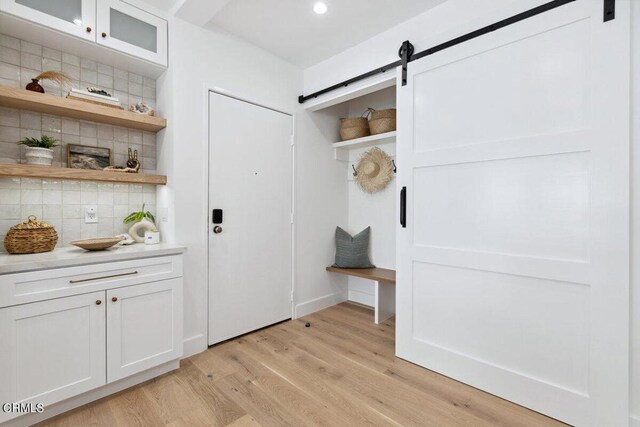 mudroom featuring a barn door and light hardwood / wood-style flooring