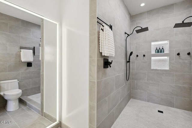 bathroom with tile patterned floors, toilet, and tiled shower