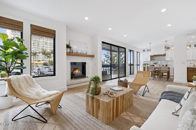 living area featuring light wood finished floors, recessed lighting, baseboards, and a lit fireplace