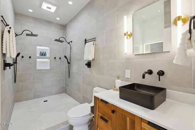 bathroom featuring toilet, backsplash, a tile shower, tile walls, and vanity