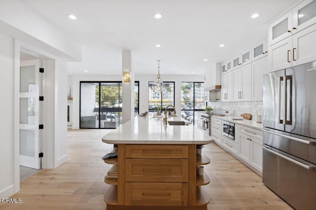 kitchen with open shelves, a sink, stainless steel appliances, light wood-style floors, and light countertops