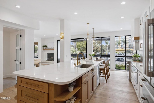 kitchen with a sink, open shelves, light wood-type flooring, and a wealth of natural light