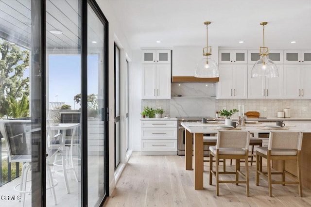 kitchen with white cabinetry, light countertops, high end range, and tasteful backsplash