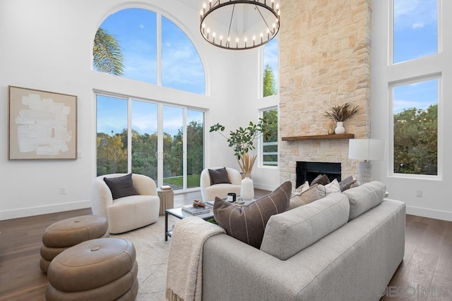 living room featuring a towering ceiling, a chandelier, a fireplace, and dark hardwood / wood-style floors