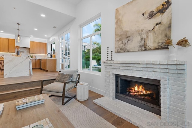 living room featuring sink, light hardwood / wood-style flooring, and a fireplace