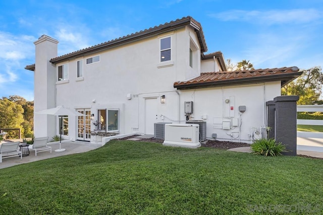 back of house featuring a lawn, central air condition unit, and a patio area