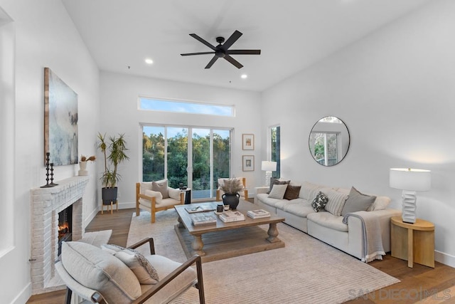 living room featuring light wood-type flooring, ceiling fan, and a fireplace