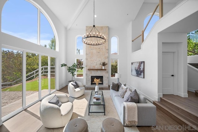 living room with an inviting chandelier, plenty of natural light, a fireplace, high vaulted ceiling, and beamed ceiling