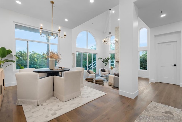 dining space with a high ceiling, a chandelier, and hardwood / wood-style flooring