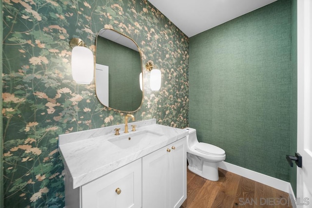 bathroom featuring wood-type flooring, toilet, and vanity