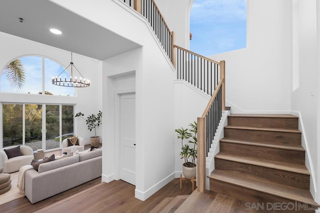 stairs featuring hardwood / wood-style flooring, a high ceiling, and a chandelier