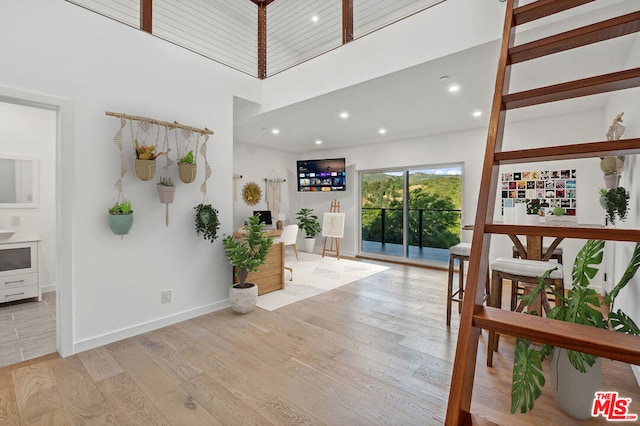 foyer entrance featuring a towering ceiling and light wood-type flooring