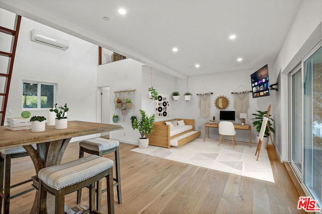 dining space with light hardwood / wood-style floors and a wall mounted air conditioner