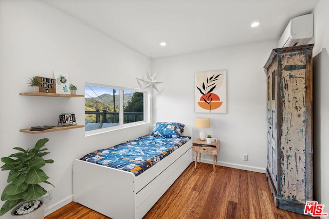 bedroom featuring hardwood / wood-style flooring and a wall mounted air conditioner