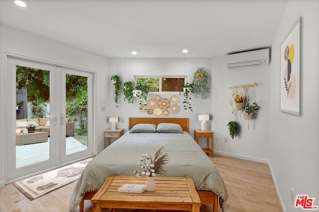 bedroom with an AC wall unit, access to exterior, french doors, and light hardwood / wood-style floors