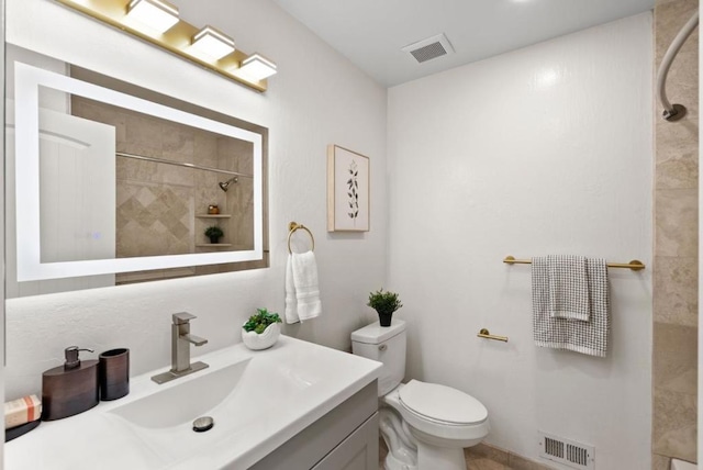 bathroom featuring vanity, toilet, and a tile shower