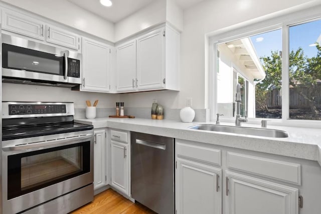 kitchen featuring white cabinetry, sink, light hardwood / wood-style flooring, and stainless steel appliances