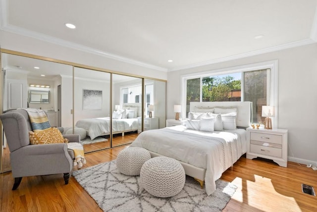 bedroom featuring ornamental molding, light hardwood / wood-style flooring, and a closet