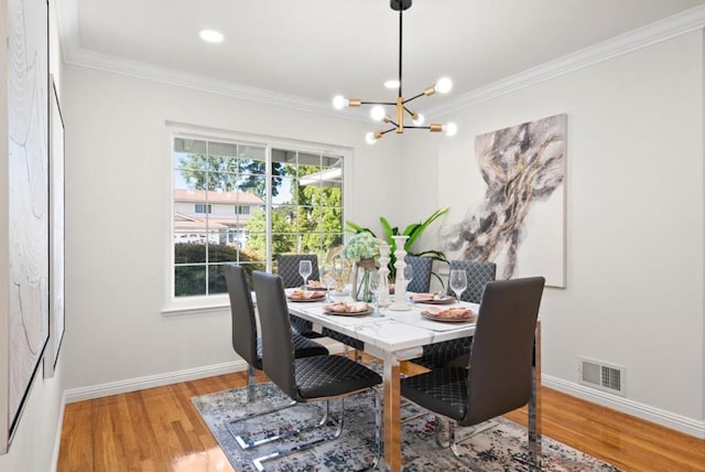 dining area featuring crown molding, hardwood / wood-style flooring, and a notable chandelier