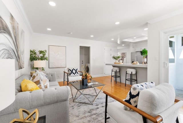 living room with washer / clothes dryer, crown molding, and light hardwood / wood-style floors