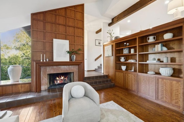 sitting room featuring dark wood-type flooring, a high end fireplace, and vaulted ceiling with beams