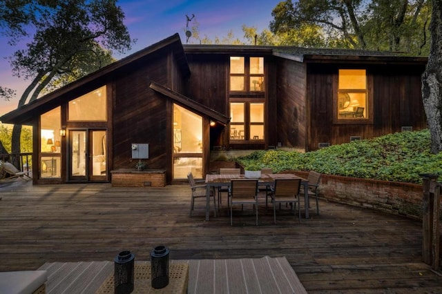 back house at dusk with a wooden deck