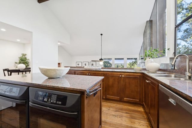 kitchen featuring sink, vaulted ceiling with beams, a center island, stainless steel dishwasher, and light wood-type flooring