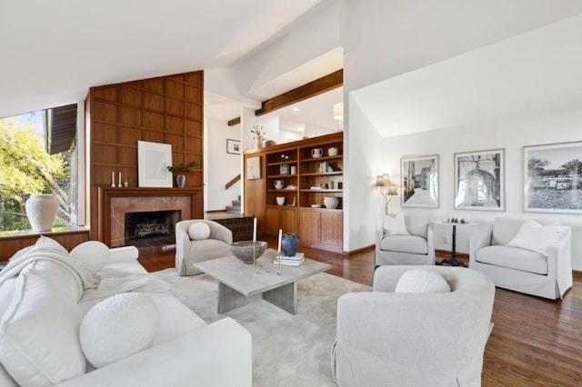 living room featuring a tiled fireplace, lofted ceiling with beams, and hardwood / wood-style floors