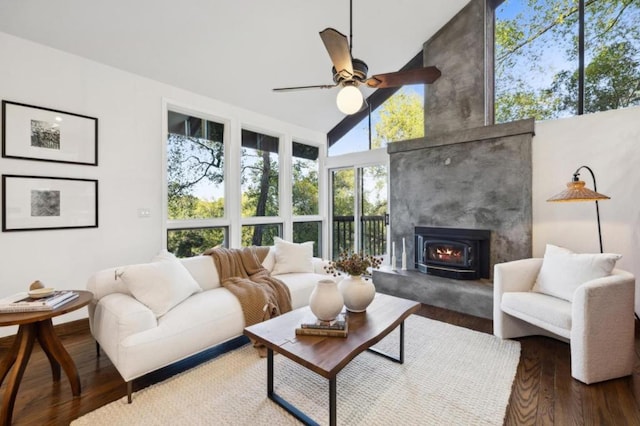 living room featuring a high ceiling, hardwood / wood-style flooring, ceiling fan, and a wood stove