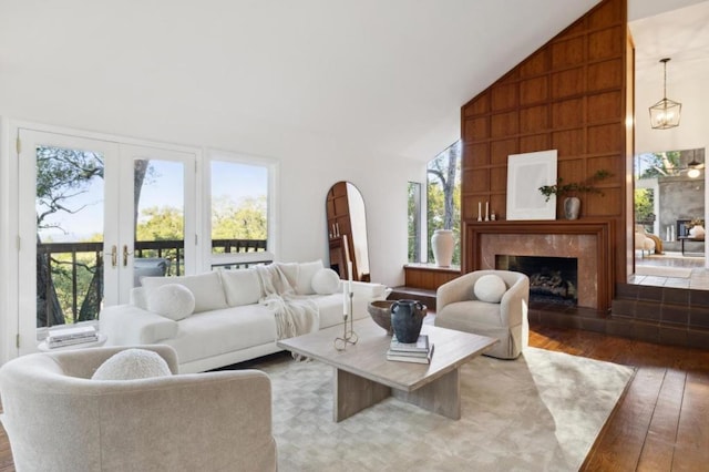 living room with french doors, wood-type flooring, a fireplace, and high vaulted ceiling