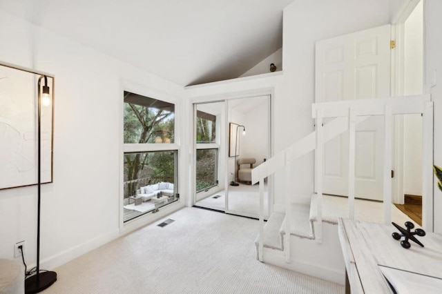 interior space featuring vaulted ceiling and light colored carpet