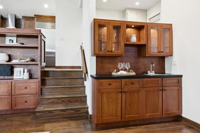 bar featuring dark wood-type flooring, sink, and decorative backsplash