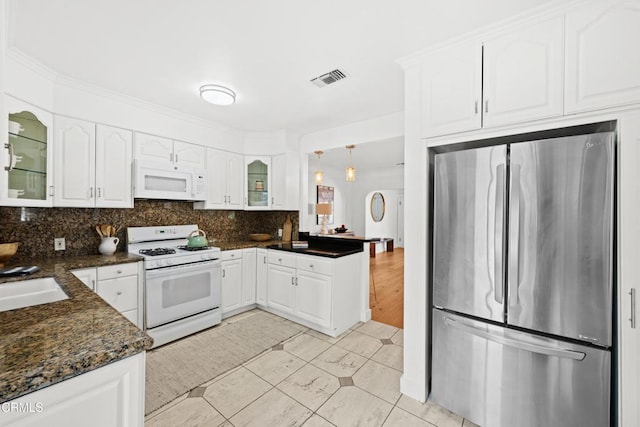 kitchen featuring white appliances, white cabinetry, dark stone countertops, decorative backsplash, and light tile patterned floors