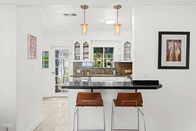 kitchen with pendant lighting, white cabinets, tasteful backsplash, kitchen peninsula, and light tile patterned floors