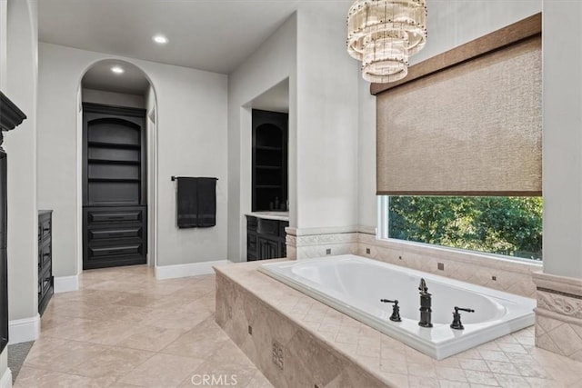 bathroom featuring vanity, tile patterned flooring, a chandelier, and tiled tub