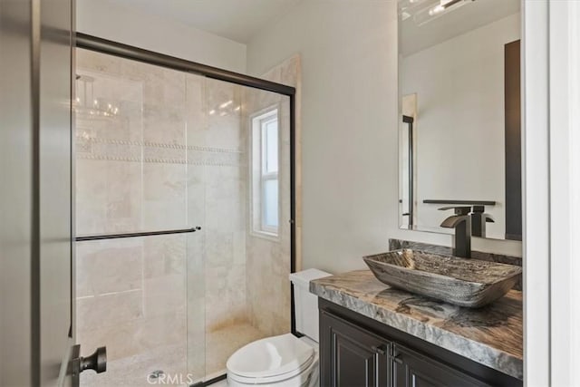 bathroom featuring a shower with door, toilet, and vanity