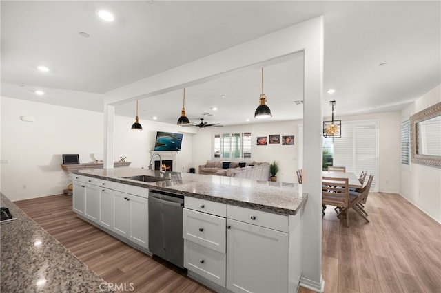 kitchen featuring ceiling fan, pendant lighting, stainless steel dishwasher, sink, and white cabinetry