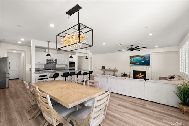 dining room featuring ceiling fan, sink, and light wood-type flooring